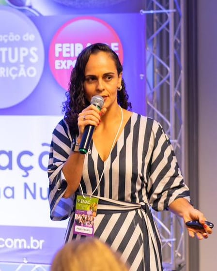 Francine Sinnott palestrando em um encontro de nutrição, com o microfone na mão.